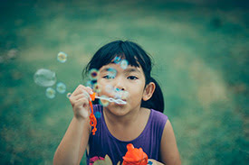 Young girl blowing bubbles at the camera
