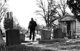 Man walking in a graveyard with flowers