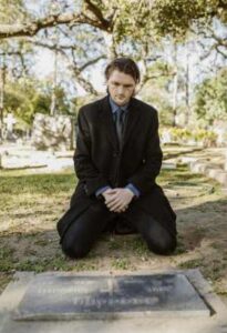 Man Praying At Gravestone