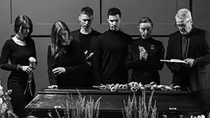Family standing over a casket